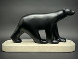 statue d'un ours noir sur un socle blanc, sur fond gris
