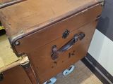 a brown trunk sitting on wheels next to a wall