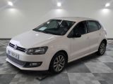 the white volkswagen polo is parked in a room with a checkered floor