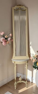 a mirror and a vase of flowers in the corner of a room
