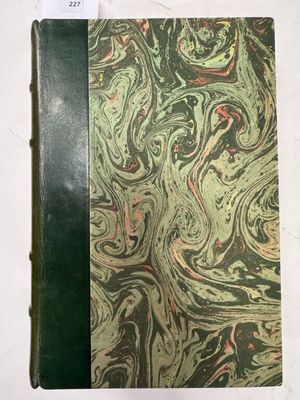 un vieux livre à la couverture verte posé sur une table blanche