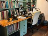 a desk with a chair in front of a bookshelf filled with books