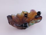 a small bowl with black beads on it on a white surface