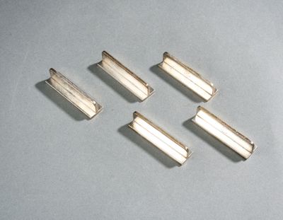 quatre pièces métalliques argentées sont disposées sur une surface grise