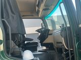 a green truck with a hard hat in the driver ' s seat