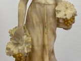 statue d'une femme tenant un panier de fleurs posé sur une table en bois
