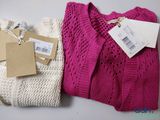 two sweaters with tags on them sitting next to each other