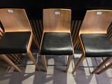 four wooden chairs are lined up against a wall in a room