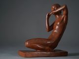 statue of a woman sitting on a wooden base with her hands on her face
