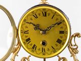 a gold clock with roman numerals and a mirror in the background