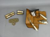 un étui en cuir sur lequel sont rangés un couteau, une cuillère et d'autres objets