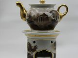 a tea pot on top of a stand with a clock on it
