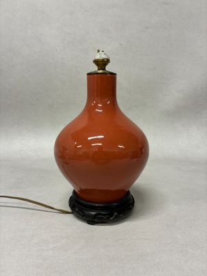 a red vase with a bird on top of it