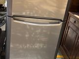 a stainless steel refrigerator in a kitchen with wood cabinets
