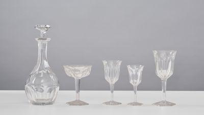 five wine glasses and a decanter sitting on a table