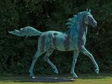 une statue représentant un cheval au galop dans l'herbe