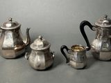 three pieces of silver tea and coffee set on a table