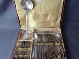 a lot of silverware in a case with a spoon and spoon rest