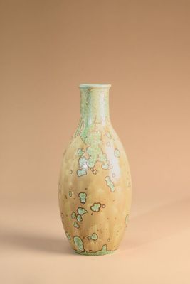 a green vase sitting on a beige surface