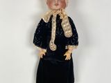 a doll that is wearing a black dress and a hat