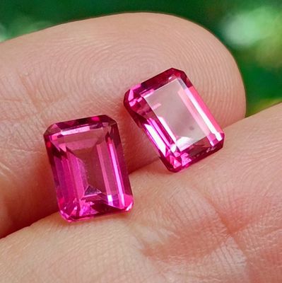 pair of pink tourmaline cut stones on a person ' s finger