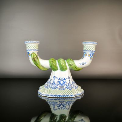 a blue and white vase with a green handle on a black table