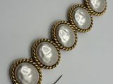 a close up of a gold bracelet with pearls on it