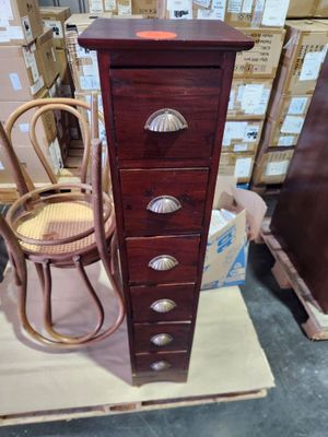 a tall wooden chest of drawers next to a wicker chair