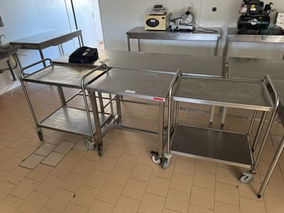 plusieurs tables et chaises en acier inoxydable dans une cuisine au sol carrelé