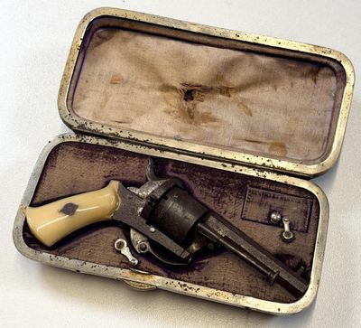 un petit pistolet dans un étui posé sur une surface blanche