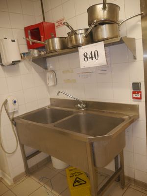 un évier en acier inoxydable dans une cuisine, avec une affiche accrochée au mur