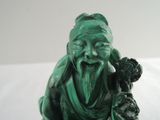 a green statue of a man holding a flower