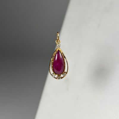 un pendentif en forme de larme, en or et rubis, sur un fond blanc