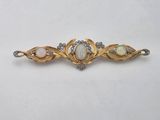 a gold and white broochle with oplites and diamonds