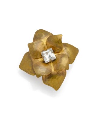 an image of a gold flower brooch with a diamond in the center
