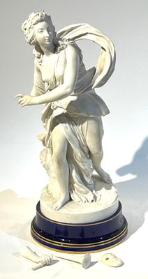 une statue représentant une femme tenant un oiseau, posée sur un socle