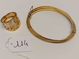 un gros plan d'un bracelet et d'une bague en or posés sur une surface blanche
