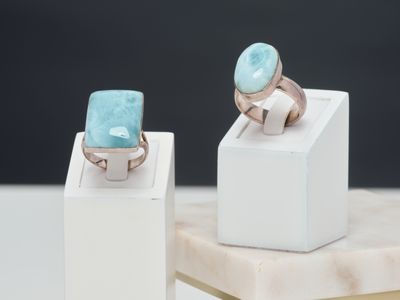 une paire de bagues ornées de pierres turquoise, posées sur un socle blanc