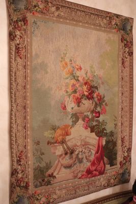 a tapestry hanging on the wall next to a vase of flowers