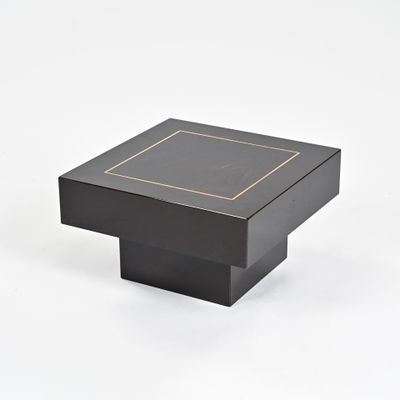 une table basse carrée noire avec un bord doré sur le plateau