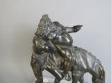 une statue en bronze représentant un garçon et un chien, posée sur un socle