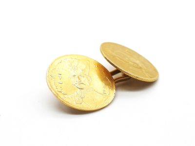 des boutons de manchette en forme de pièces d'or sur une surface blanche, avec un fond blanc