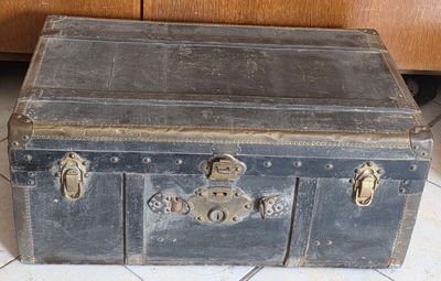 une vieille malle posée par terre à côté d'une armoire