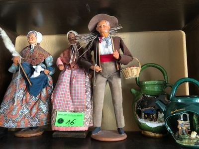trois figurines représentant des personnes, posées côte à côte sur une étagère