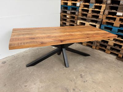 une photo d'une table en bois avec des pieds en métal dans un entrepôt