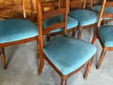 six chairs with blue upholstered seats in front of a wooden wall