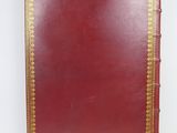 an old red leather book with gold trimmings on a white background