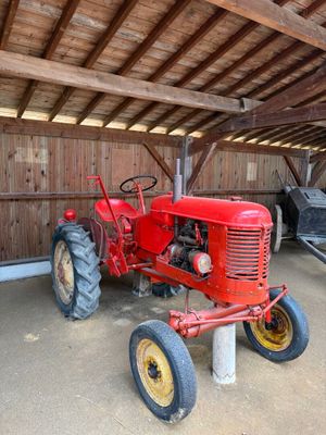un tracteur rouge garé dans une grange au toit en bois