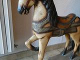 un cheval à bascule en bois posé sur un skateboard, lui-même posé sur un sol carrelé