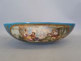 a blue bowl with a painting on it on a table